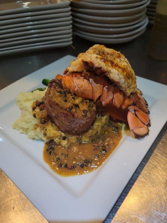 A plate of food with lobster, potatoes and meat.