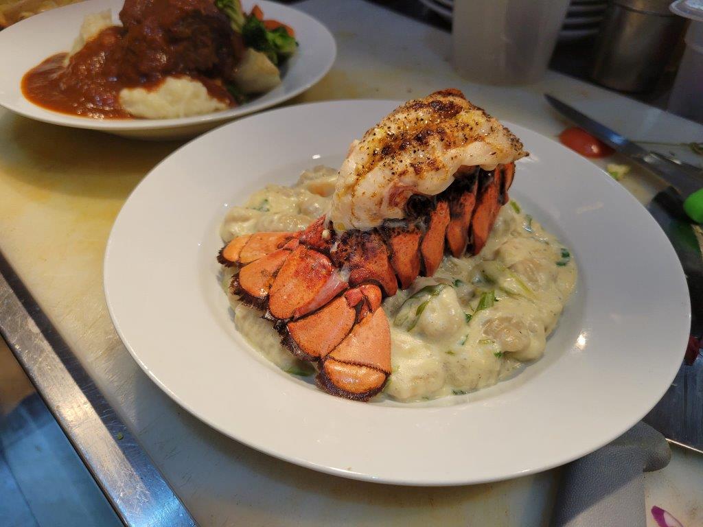 A lobster dinner with mashed potatoes and gravy.