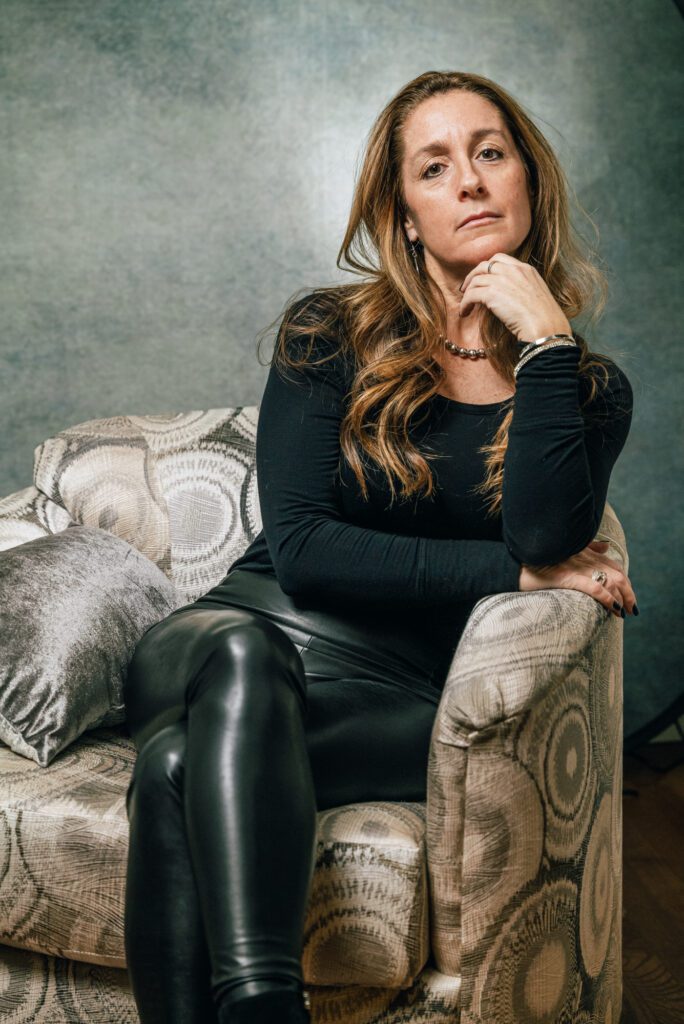 A woman sitting on top of a couch in black leather pants.