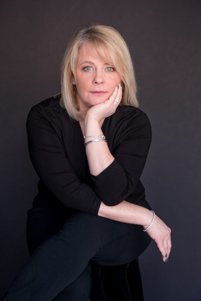 A woman sitting on the ground with her hand under her chin.