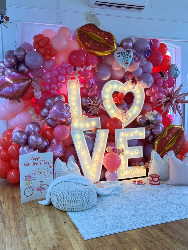 A room with balloons and lights that say " love ".