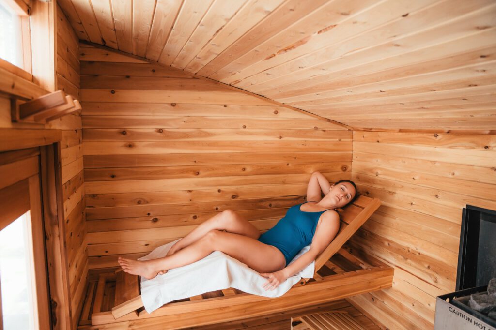 A woman laying on a wooden bed in a sauna.