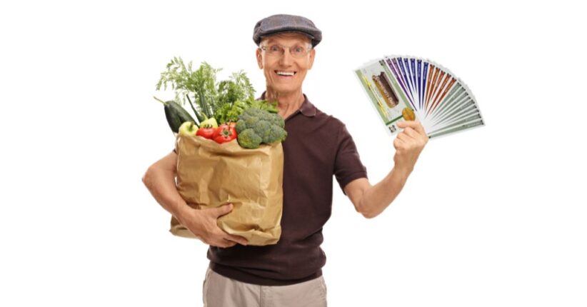 A man holding a bag of vegetables and a fan